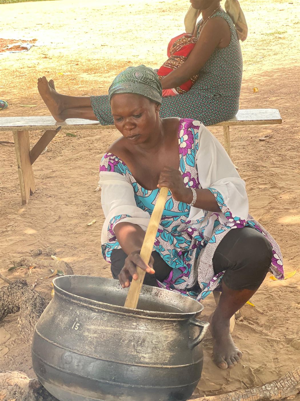 A woman stirring a pot of groundnut paste over the fire